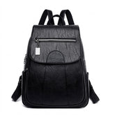 Sac à dos en cuir noir Marceline à rabat avec poche zippée, vue de face sur fond blanc
