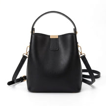 Petit sac seau en cuir noir Sidonie avec patte à plaque dorée, vue de face sur fond blanc