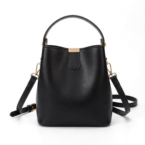Petit sac seau en cuir noir Sidonie avec patte à plaque dorée, vue de face sur fond blanc