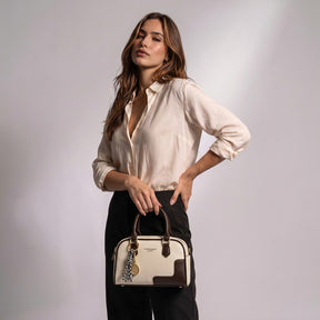 Femme tenant le mini sac bowling Iris blanc cassé et marron par ses anses