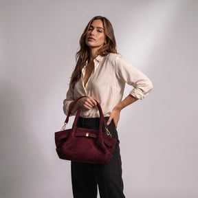 Femme portant le sac trapèze Flore bordeaux à la main