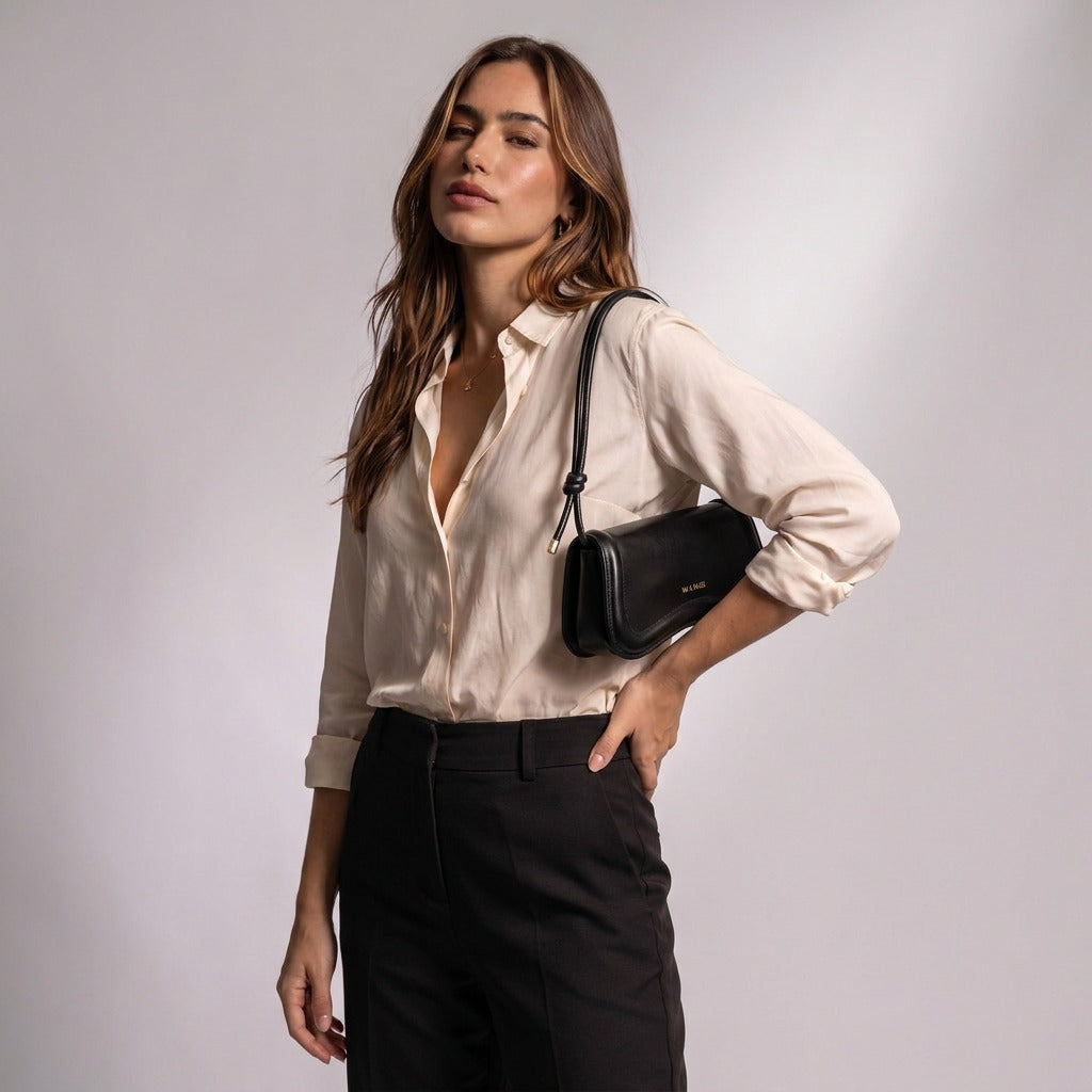 Femme portant le sac baguette Domitille noir sous le bras, main sur la taille