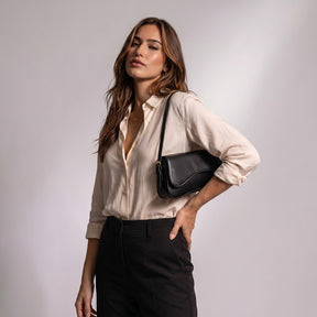 Femme portant le sac baguette Romy noir sous le bras, main sur la taille