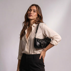 Femme portant le sac Garance noir sous le bras, main sur la taille