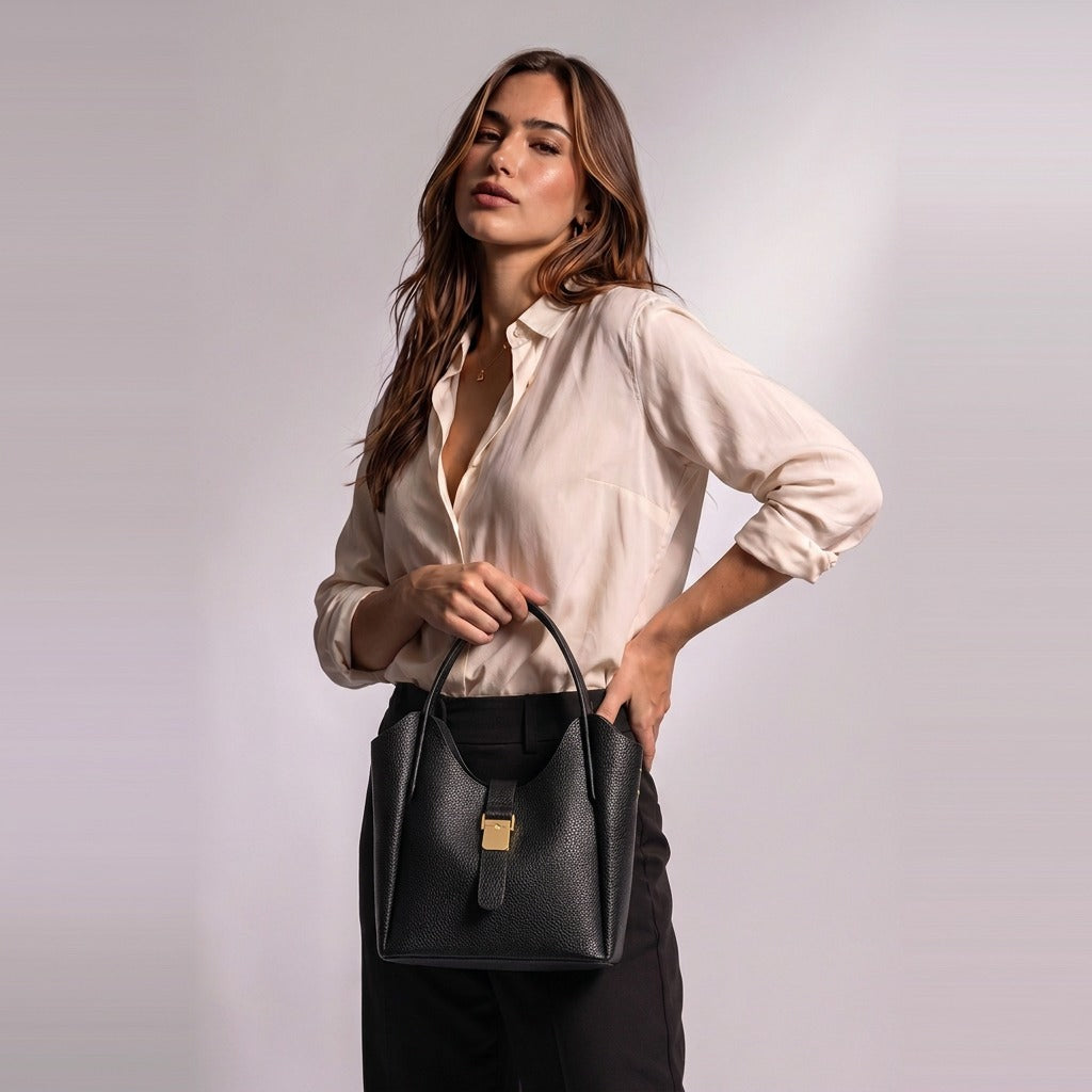 Femme tenant à la main le sac seau en cuir Ondine noir par son anse ronde