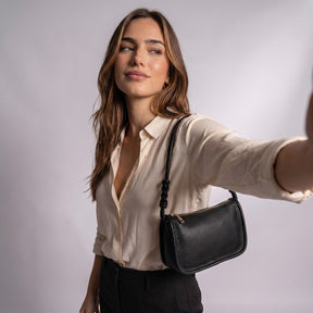 Femme portant le sac Capucine noir sous le bras