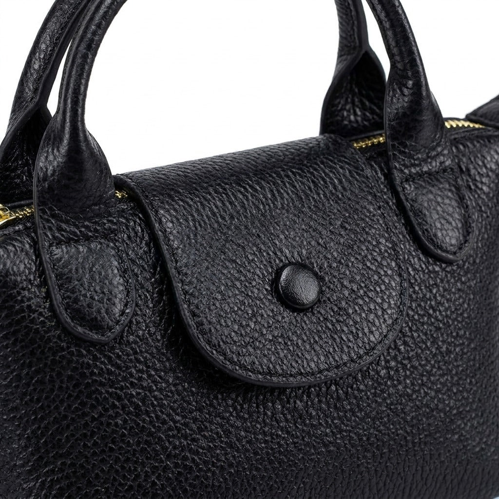 Détail du rabat à bouton-pression et des anses roulées du sac Noémie noir