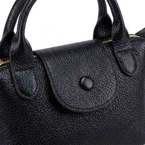 Détail du rabat à bouton-pression et des anses roulées du sac Noémie noir
